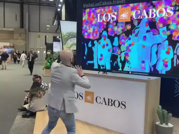 Visitors holding their printed pointillist portraits at the Los Cabos stand, FITUR Madrid