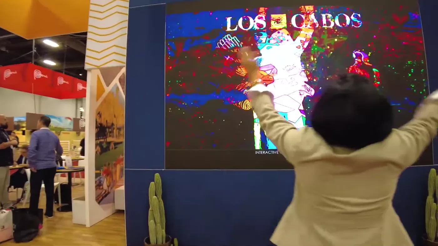 Visitor raising arms as the wall explodes in color
